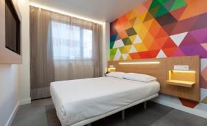 1 dormitorio con 1 cama y una pared colorida en Vértice Roomspace, en Madrid