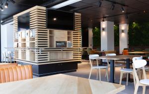 a restaurant with tables and chairs and a flat screen tv at Vértice Roomspace in Madrid