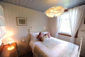 a bedroom with a bed and a window and a chandelier at The Green House at Tathhill in Beattock