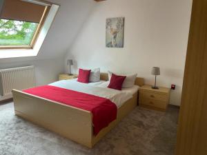 a bedroom with a bed with red sheets and a window at Röhrshof in Bispingen