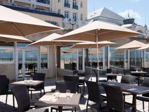 a restaurant with tables and chairs with umbrellas at Le Grand Hotel de Cabourg - MGallery Hotel Collection in Cabourg