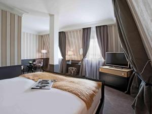 a hotel room with a large bed and a television at Le Grand Hotel de Cabourg - MGallery Hotel Collection in Cabourg