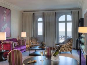 a living room with a purple couch and chairs at Le Grand Hotel de Cabourg - MGallery Collection in Cabourg