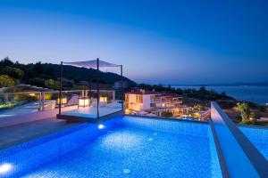 eine Villa mit einem Pool in der Nacht in der Unterkunft Villa D'Oro - Luxury Villas & Suites in Paliouri