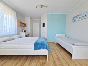 two beds in a bedroom with blue walls and wooden floors at Chatka Morska 3 in Karwia