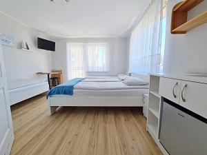 a white bedroom with a bed and a wooden floor at Chatka Morska 3 in Karwia +19 photos