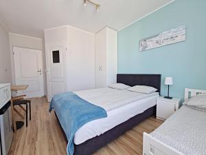 a white bedroom with a large bed with a blue blanket at Chatka Morska 3 in Karwia