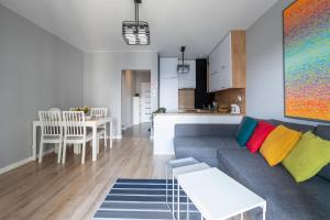 ein Wohnzimmer und eine Küche mit einem Sofa und einem Tisch in der Unterkunft Luxury in City -1-Bright-Secured-Free Parking in Łódź
