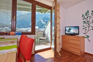 a bedroom with a bed and a television and a balcony at SkyLounge Mayrhofen in Mayrhofen
