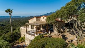 una casa su una collina con una palma di Villa L'Arbousière a Porto Vecchio