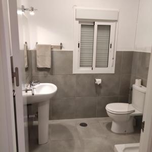 a bathroom with a sink and a toilet and a mirror at Apartamentos Costa de la Luz Béjar 28-30 in Huelva