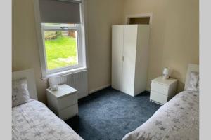 um quarto com 2 camas e uma janela em Beautiful two bedroom flat by the Loch em Balloch