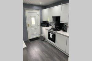 uma cozinha com armários brancos e um forno com placa de fogão em Beautiful two bedroom flat by the Loch em Balloch