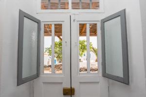 an open door with two windows on a white building at Στην Ωραία Πλάκα in Plaka Milou