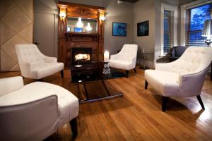 a living room with white chairs and a fireplace at Le Pleasant Hôtel & Café in Sutton