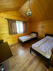 a bedroom with two beds in a wooden cabin at Hanul Arcașului in Voila