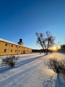 a snow covered street with a building and a tree at Falstadsenteret Hotell - Museum, minnested og senter for menneskerettigheter in Levanger