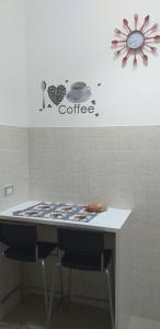 uma mesa com duas cadeiras e uma placa de café na parede em Piccola Azzurra Branch em Comiso