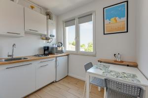 uma cozinha com armários brancos e uma mesa com cadeiras em Lion Apartments - Korfu em Sopot