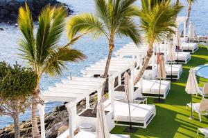 a row of white chairs and palm trees at a resort at Hotel LIVVO Puerto de Mogán in Puerto de Mogán