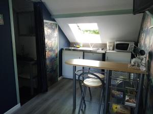 een kleine keuken met een tafel en een magnetron bij Petit Studio Mansardé - accès indépendant in Neuilly