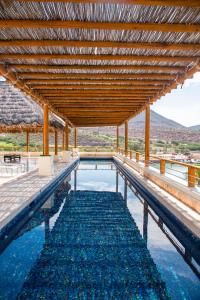 a swimming pool with a wooden roof and blue water at Hotel Indigo La Paz Puerta Cortes by IHG in La Paz