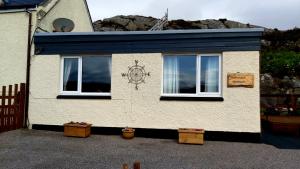 a house with a blue roof and two windows at Achmelvich View self catering in Lochinver