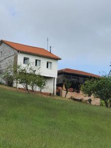 une maison blanche avec un toit rouge et un champ vert dans l'établissement Casa Don Diego, à Perlora
