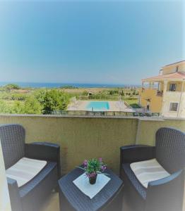 a balcony with two chairs and a table and a pool at Appartamenti Abbaidda in Valledoria