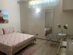 ein Schlafzimmer mit einem Bett und einem Tisch mit einer Blumenvase in der Unterkunft Villa relax cappuccini in Galatone