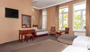 a hotel room with two beds and a desk at Margo Palace Hotel in Tbilisi City