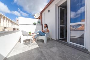 a woman sitting in a chair on a balcony at Palazzo Lombardi Al Vicolo in Sassari