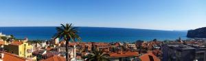 uma vista para uma cidade com uma palmeira e o oceano em Appartamento Caterina Finale Ligure em Finale Ligure