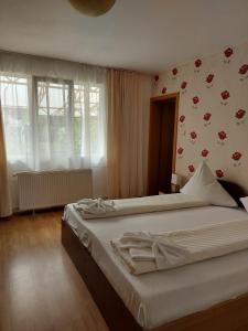 a bedroom with a large bed with white sheets at Pensiunea Gheorghita in Haţeg
