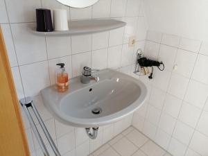 a white sink in a white tiled bathroom at Gästehaus Herbert Kappes in Zeltingen-Rachtig +13 photos