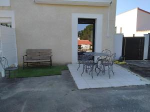 eine Terrasse mit einem Tisch, Stühlen und einer Bank in der Unterkunft logement entre mer et montagne in Roujan