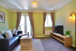 a living room with a blue couch and a tv at Felton House in Stafford