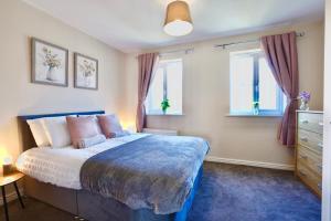 スタッフォードにあるFelton Houseの青いベッドと2つの窓がある寝室