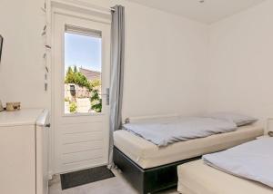 een slaapkamer met 2 bedden en een deur met een raam bij De Zandput 23 Zoutelande in Zoutelande