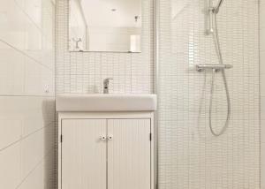 een witte badkamer met een wastafel en een douche bij De Zandput 23 Zoutelande in Zoutelande +16 foto's