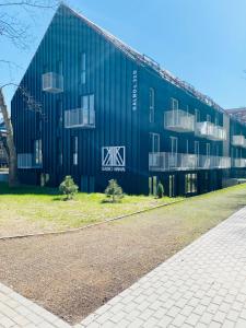 耶德库安特Rimos apartamentai Juodkranteje的一座蓝色的大建筑,其一侧设有窗户