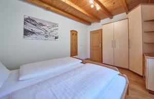 a bedroom with a large white bed and wooden cabinets at Appartements 4-You in Saalbach Hinterglemm