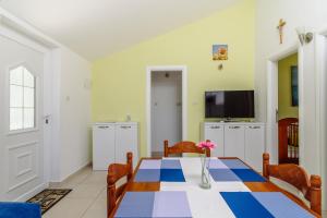 une salle à manger avec une table et une télévision dans l'établissement Skoro Residence, à Vinišće