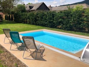 a pool with two chairs and a swimming pool at Diókert Vendégház in Komjáti