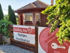 una pequeña casa con un cartel delante en Nyirjes Vendégház en Balassagyarmat