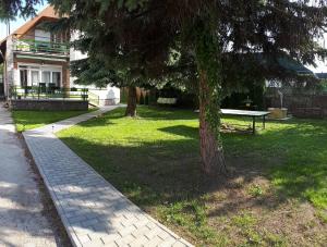 a park with two trees and a bench in the grass at Széplaki Nyár Vendégház in Siófok