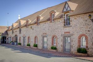a large brick building with windows on a street at Logis Hotel Oasis in Villaines-la-Juhel