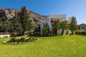 una casa con un cortile verde con una montagna sullo sfondo di Villa Sole Mare a Pefki Rhodes