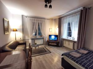 Una sala de estar con una cama, un sofá y un televisor. en Cozy room in the Old Town, en Varsovia