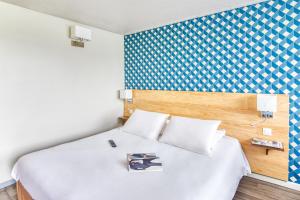 a hotel room with a bed with a book on it at Kyriad Montauban Sud - Albasud in Montauban